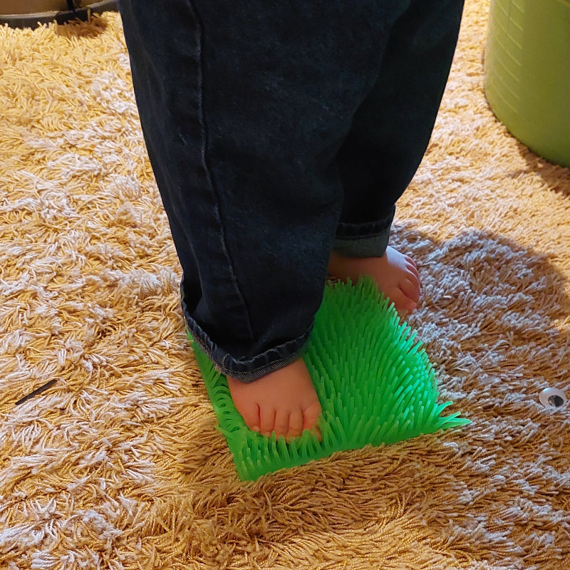 fluffy mat als sensoriek matje voor blotevoetenpad, baby staat op matje