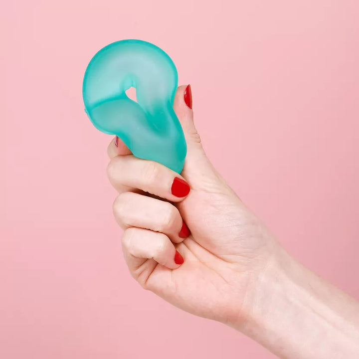 speks gump loop groen in hand met rode vingernagels en roze achtergrond, fidget van speks
