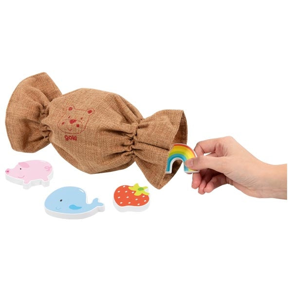 Hand haalt een houten motief uit het stoffen zakje van het Fühlmemo spel met tactiele kaarten