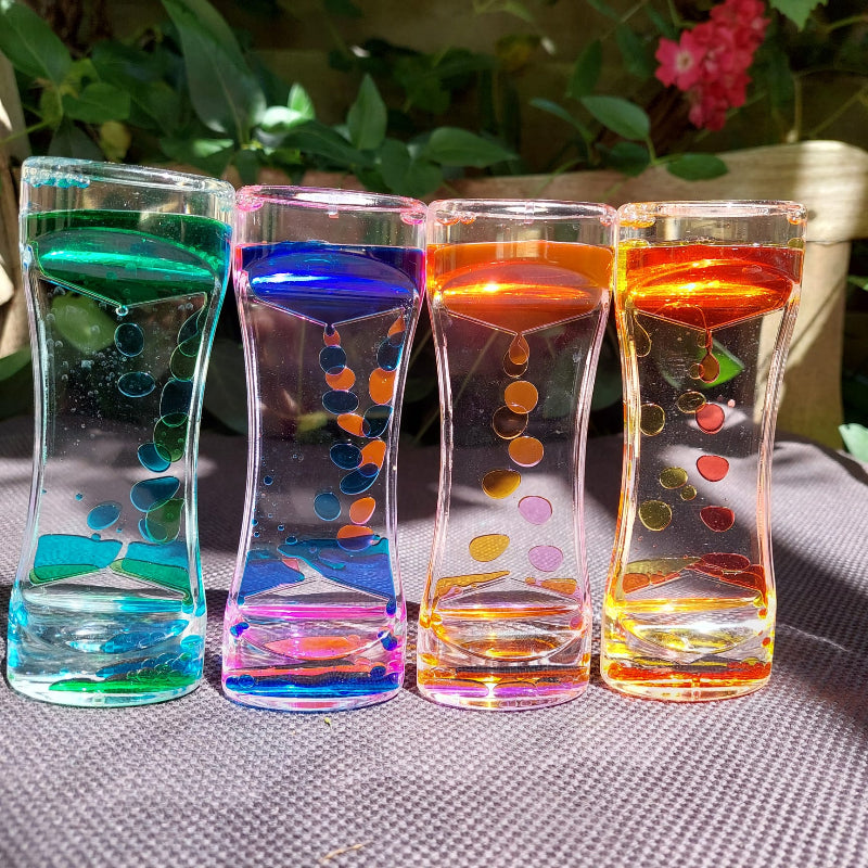 liquid öl sanduhr timer in vier farben, auf tisch im garten mit rosen im Hintergrond, sensorik material