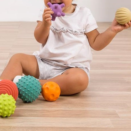 Jong kind speeltn met de set rubber baby ballen, 2 ballen in de hand – sensorisch speelgoed voor fijne en grove motoriek