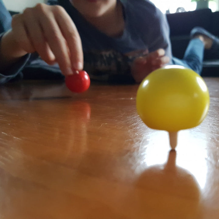 goki Omkeertol die op zijn steel tolt. kind aan het spelen met twee tollen