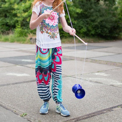 buitenspeel Diabolo, kind speelt buiten met een draaiende diabolo en oefent circus trucjes