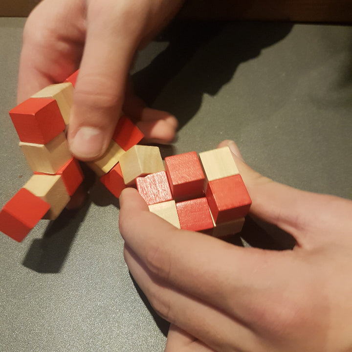 Handen draaien en vouwen aan de houten puzzelslang – slangenkubus stimuleert motoriek en ruimtelijk inzicht