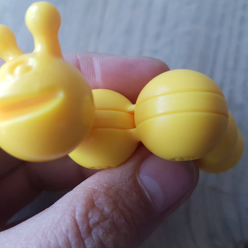 Flexibele rups uit SmartGames Apple Twist die rond de appel kan worden gedraaid in hand